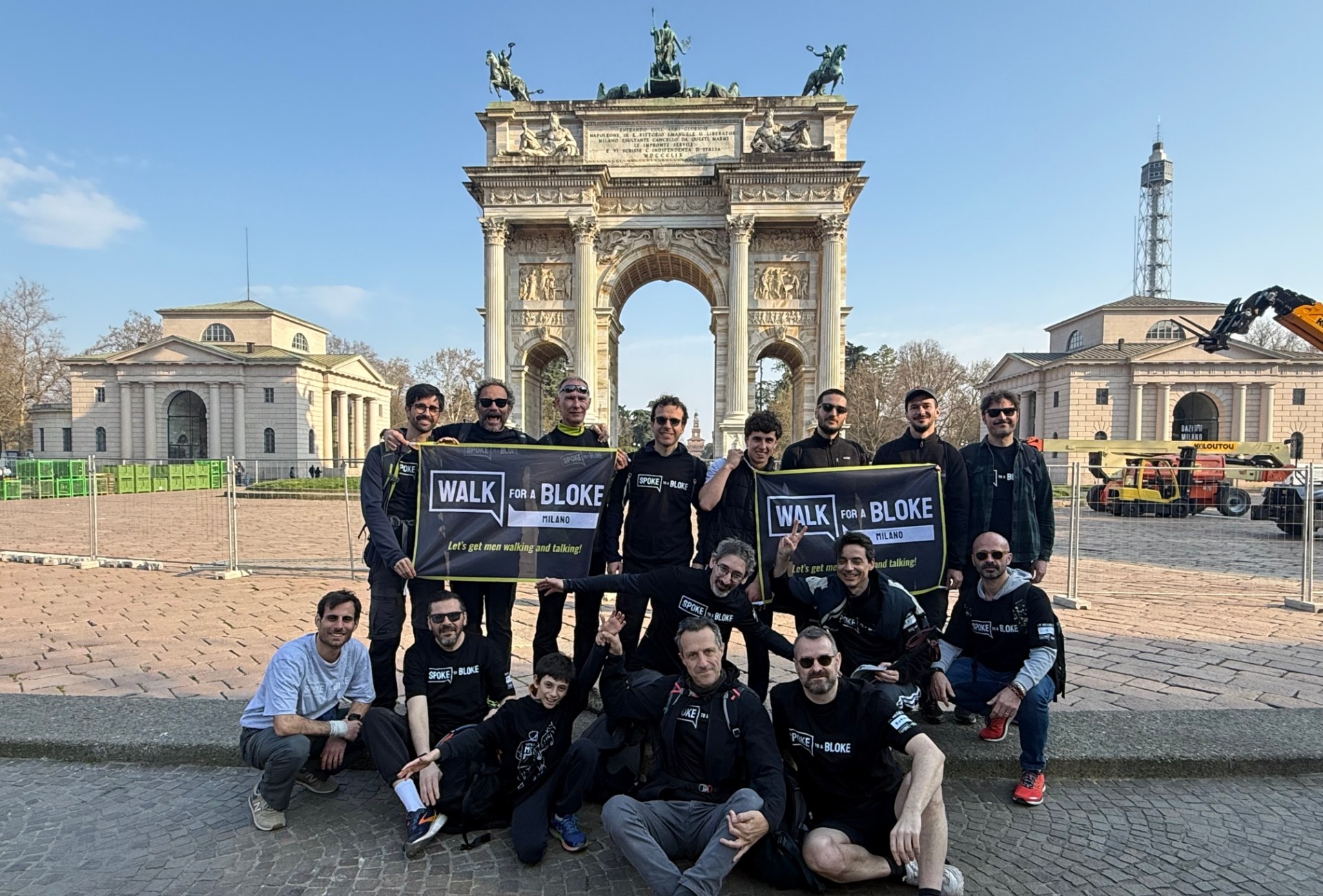 Milan walkers holding Walk for a Bloke Milano banners in front of the Arco della Pace